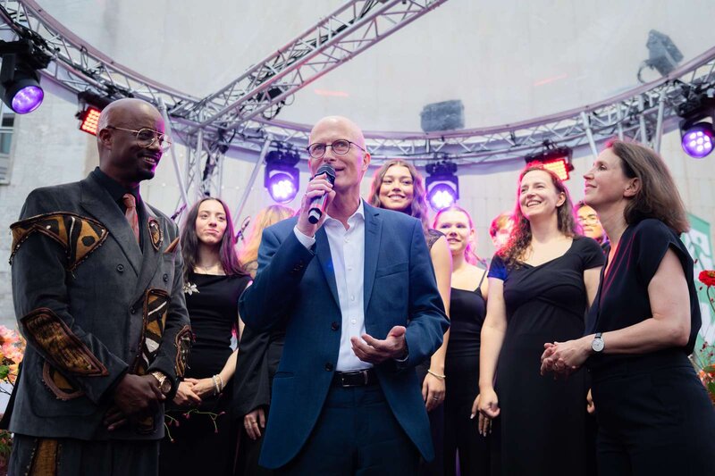 Menschen auf einer Bühne, sprechen und singen gemeinsam.
