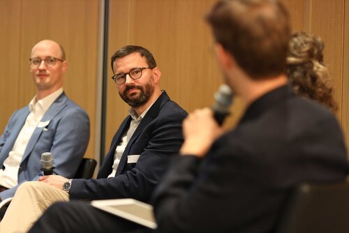Drei Personen sitzen in einer Diskussion, Mikrofone in der Hand. Impressionen der Veranstaltung "Exzellenz durch Kongresse" mit Podiumsdiskussion und Networking.