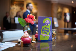 Tisch mit Blumen, Flyer für Open Hotel Days und Figuren.
