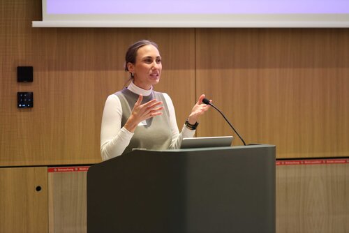 Eine Person spricht am Podium während einer Präsentation oder Konferenz. Impressionen der Veranstaltung "Exzellenz durch Kongresse" mit Podiumsdiskussion und Networking.