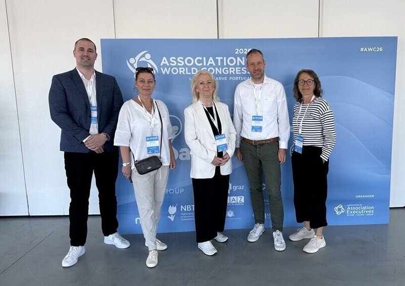 Fünf Personen stehen vor einem Banner des Association World Congress.