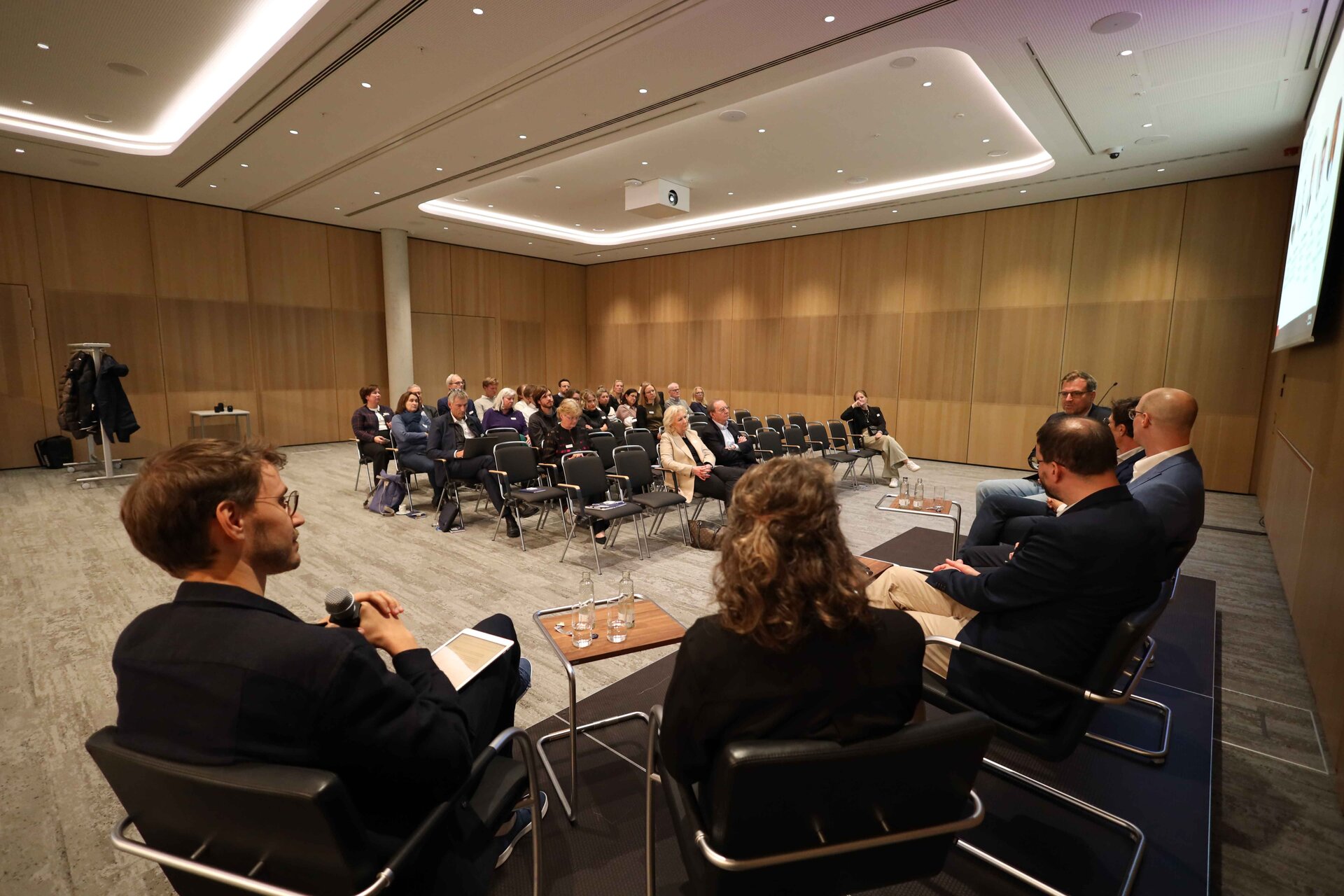 Diskussionsrunde in einem Konferenzraum mit Publikum. Impressionen der Veranstaltung "Exzellenz durch Kongresse" mit Podiumsdiskussion und Networking.