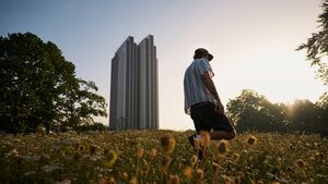 Ein junger Mann ist von hinten zu sehen. Er geht durch Planten und Blomen, im Hintergrund sieht man das Radisson und die Abendsonne im Gegenlicht