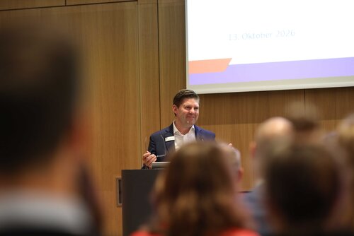 Ein Mann spricht zu einem Publikum bei einer Veranstaltung. Impressionen der Veranstaltung "Exzellenz durch Kongresse" mit Podiumsdiskussion und Networking.