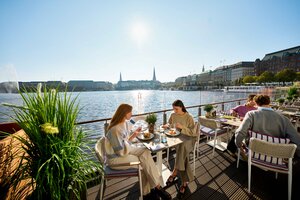 Menschen essen gemeinsam vor Alsterkulisse