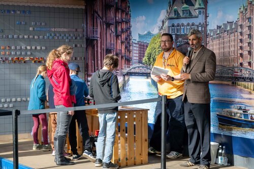 Menschen stehen an einem Tisch, sprechen und schauen auf eine Präsentation. Impressionen vom Bürgerfest zum Tag der Deutschen in Bremen.