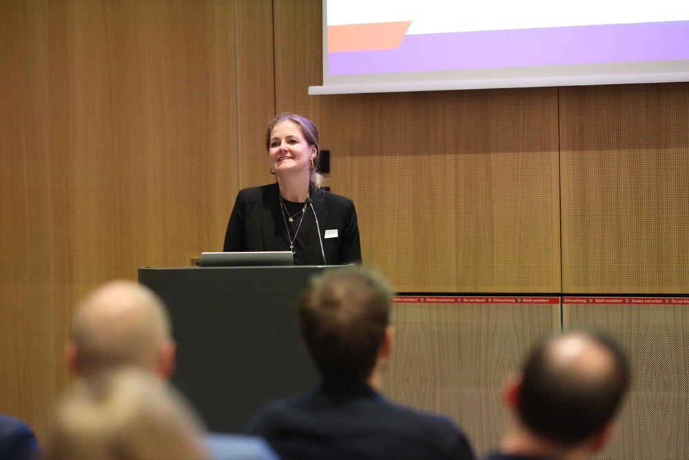 Eine Frau spricht an einem Podium vor einem Publikum. Impressionen der Veranstaltung "Exzellenz durch Kongresse" mit Podiumsdiskussion und Networking.
