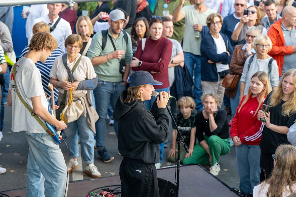 Menschenmenge hört zu, Musiker mit Gitarre und Sängerin auf Konzertbühne. Impressionen vom Bürgerfest zum Tag der Deutschen in Bremen.